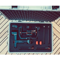 Geöffneter Koffer mit Schaumstoffeinlage, die ein Gimbal-Stabilisierungssystem und Zubehör enthält, auf Holzboden.